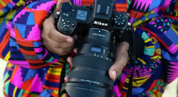 Osoba trzyma aparat Nikon Z z obiektywem na tle kolorowego ubrania.