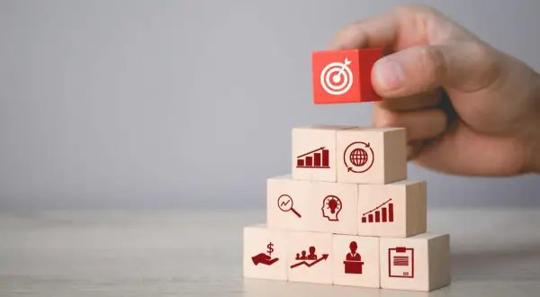 Budowanie strategii marketingowych: klocki symbolizują analizę, pomysły, wzrost, globalny zasięg i cel. Podstawa to marketing fundamentals.