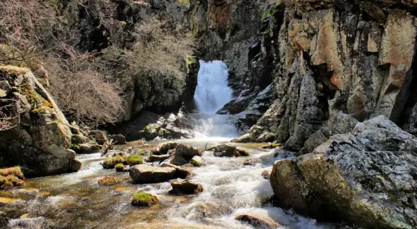 Un río serpentea entre rocas y vegetación hasta una cascada en la ruta de las cascadas del Purgatorio.