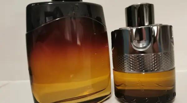 Dwa flakony perfum: jeden z gradientem od czerni do bursztynu, drugi z metalicznym wykończeniem i napisem AZZARO. Idealne na noc.