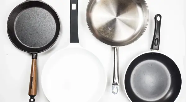 Vier Pfannen: Gusseisen, weiß beschichtet, Edelstahl und eine weitere beschichtete Pfanne. Jede aluminium oder edelstahl pfanne hat ihren Zweck.