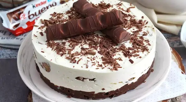 Pyszna tarta Kinder Bueno z kremem i czekoladowymi wiórkami, ozdobiona batonikami.