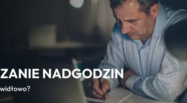 Mężczyzna pochyla się nad dokumentami, pisząc coś długopisem. Temat: rozliczanie nadgodzin, zgodnie z art. 151 kp.