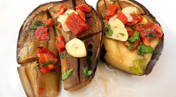 Melanzane alla sassarese, un piatto saporito con melanzane cotte, pomodori secchi, aglio e prezzemolo.