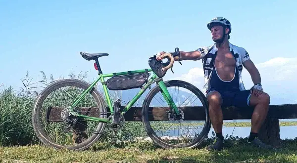 Ciclista riposa accanto alla sua bici verde, un promemoria che andare in bici fa dimagrire e dona benessere.