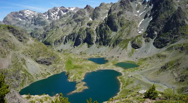 Vue panoramique sur le lac Robert et ses jumeaux, entourés de montagnes escarpées aux sommets enneigés. Un paysage alpin spectaculaire.