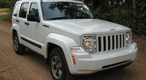 Biały Jeep Liberty 3.7 na drodze leśnej. Wiele osób szuka jeep liberty 3.7 opinie przed zakupem.
