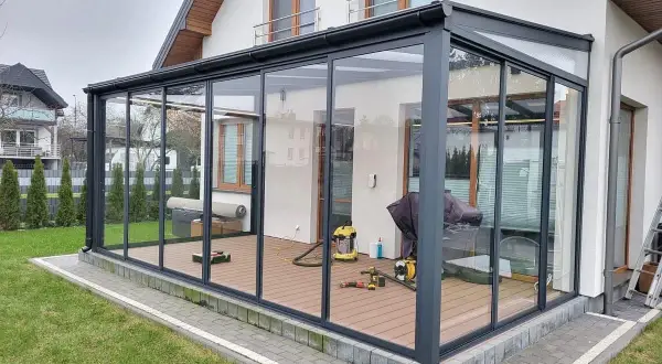 Nowoczesna szklana pergola z ruchomym dachem nad tarasem.