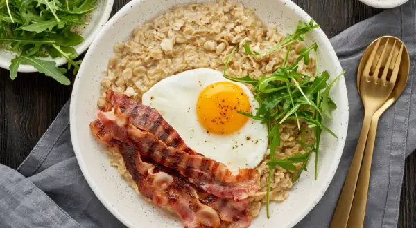Herzhaftes Frühstück: Haferflocken mit Spiegelei, Speck und Rucola. Wer sagt, dass man Haferflocken abends essen muss? Dieses Gericht ist perfekt für einen energiegeladenen Start in den Tag.