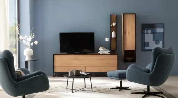Blau passt wunderbar zu Schwarz. Ein modernes Wohnzimmer mit blauen Sesseln, einem Holzbett und schwarzem Couchtisch.