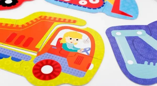 Kolorowe puzzle z pojazdami. Dziewczynka w żółtych włosach prowadzi czerwono-żółtą ciężarówkę. Obok widać fragmenty innych pojazdów, jak koparka. To świetna zabawa z **czuczu**!