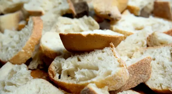 Kawałki czerstwego chleba pokrojone w kostkę i plastry, gotowe do zapiekanki.