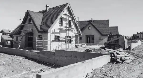 Domy w budowie, rusztowania, koparka i betonowe fundamenty. Wkrótce będzie pozwolenie na budowę i nowe domy.