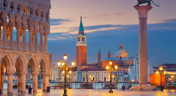 Piazza San Marco Venezia al tramonto, con il Palazzo Ducale, il Campanile e la Basilica di San Giorgio Maggiore illuminati.