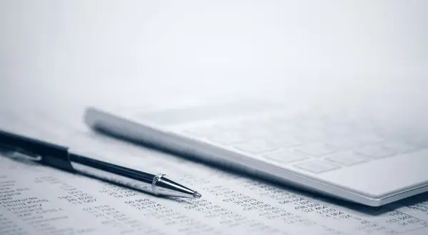 Długopis i kalkulator na arkuszu z danymi. To narzędzia pracy, które pomagają w analizie finansowej, niezbędne dla każdego, kto ma kod zawodu kierownik.