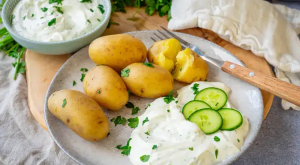 Kleine, gekochte Kartoffeln mit Kräuterquark und Gurkenscheiben – ein einfaches Gericht, das zeigt, wie vielseitig Rezepte mit Kartoffeln als Hauptspeise sein können.