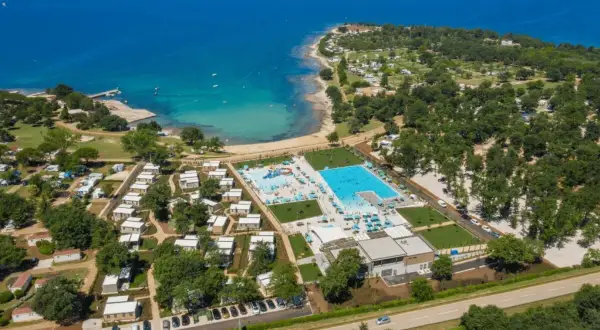 Idealne miejsce, gdzie na wakacje z dziećmi w Europie: kompleks basenów, plaża i domki kempingowe nad turkusowym morzem.