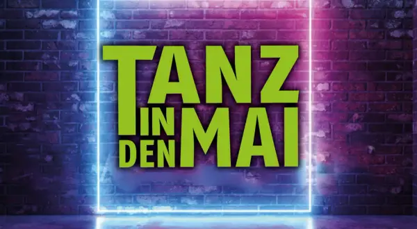 Tanz in den Mai Solingen: Grüne Schrift auf Neon-Rahmen vor Ziegelwand.