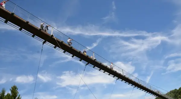 Menschen spazieren auf einer Hängebrücke im Himmel. Ein tolles geheimes Ausflugsziel in Rheinland-Pfalz für Abenteuerlustige.