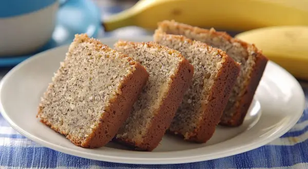 Fredriks fika: saftig banankaka i skivor på en vit tallrik, med en banan i bakgrunden.