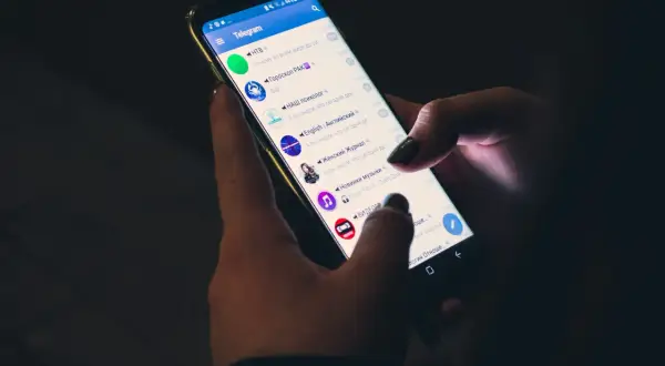 Dłonie trzymają smartfon z otwartą aplikacją Telegram. Czy telegram jest bezpieczny? To pytanie nurtuje wielu użytkowników komunikatorów.
