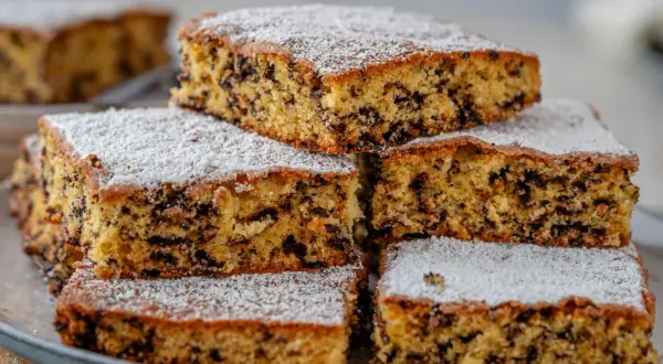 Stapel von saftigen Kuchenstücken mit Schokostückchen, bestäubt mit Puderzucker. Perfekt für einen schnellen Kuchengenuss.