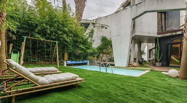 El jardín de la casa Sebastián San José invita al relax con tumbonas, piscina y columpios.