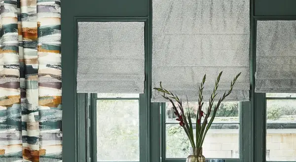 Tende a pacchetto grigie scintillanti fino al davanzale, accanto a una tenda con pennellate astratte colorate.