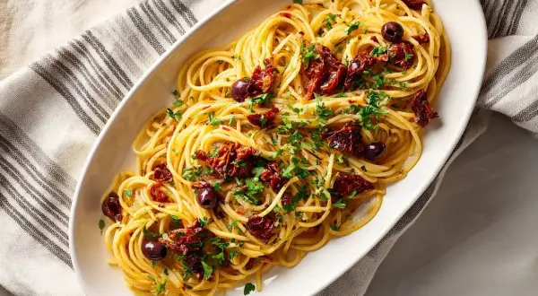 En skål med spaghetti, toppad med soltorkade tomater, oliver och persilja. En härlig pasta puttanesca.