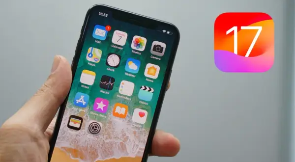 Dłoń trzyma iPhone'a z ikonami aplikacji, obok widnieje logo iOS 17.