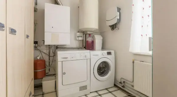 Pomieszczenie gospodarcze w domu z pralką, suszarką, bojlerem i kotłem.