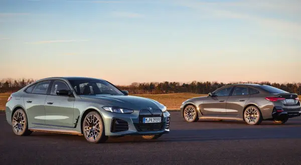 Dwa eleganckie BMW Gran Coupe, jedno zielone, drugie brązowe, stoją na asfalcie o zachodzie słońca.