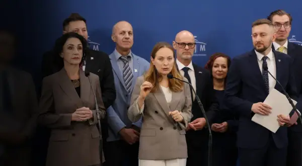 Grupa osób na tle niebieskiej ściany. Kobieta przemawia do mikrofonu, gestykulując. W tle inni mężczyźni i kobiety. Czym Polska 2050 różni się historycznie od nowoczesnej?