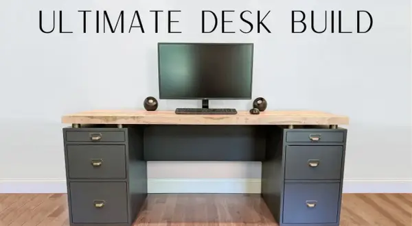 A modern DIY computer desk with a light wood top, dark gray drawers, and a monitor setup.