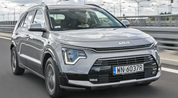 Szary Kia Niro w ruchu drogowym. Sprawdź atrakcyjną kia niro cena i wybierz swój nowy samochód.