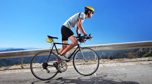 Kolarz w kasku i okularach pokonuje górską trasę. Czy 100 km na rowerze to dużo? Dla niego to wyzwanie!