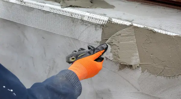 Application d'un enduit isolant extérieur avec une truelle, renforçant la façade.
