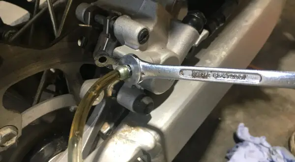 Klucz nasadowy odkręca odpowietrznik podczas wymiany płynu hamulcowego w motocyklu.