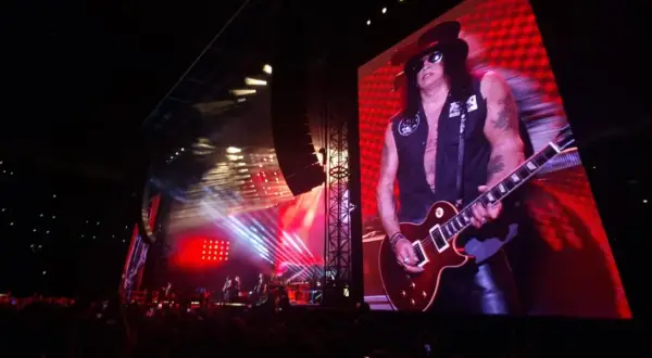 Slash z Guns N' Roses gra na gitarze na wielkim ekranie podczas koncertu.