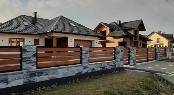 Nowoczesne ogrodzenie domu z betonowych bloczków i drewnianych desek. Świetny pomysł na ogrodzenie domu, który podkreśla jego styl.