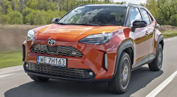 Pomarańczowy Toyota Yaris GR Sport na drodze. Wiele pozytywnych toyota yaris opinie potwierdza jego sportowy charakter i atrakcyjny wygląd.