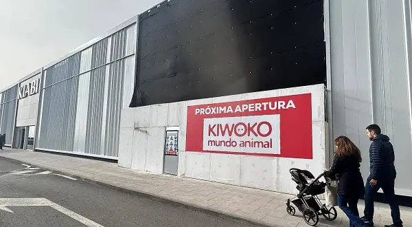 Fachada de tienda Kiwoko con anuncio de próxima apertura y gente paseando.