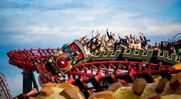 Energylandia pociąg z pasażerami wznosi się na torach kolejki górskiej, wszyscy krzyczą z radości.