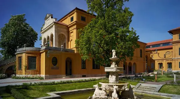 Der kunstbau lenbachhaus mit seinem gelben Anbau und dem Brunnen im Garten.