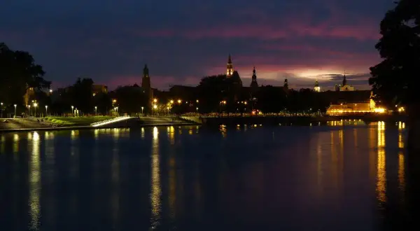 Zachód słońca nad Odrą we Wrocławiu. Idealne miejsce, by zastanowić się, co robić we Wrocławiu wieczorem, podziwiając iluminacje miasta.