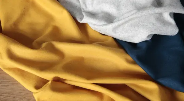 Miękki, lejący się rayon materiał w kolorze musztardowym, szarym i granatowym, ułożony w fałdy.
