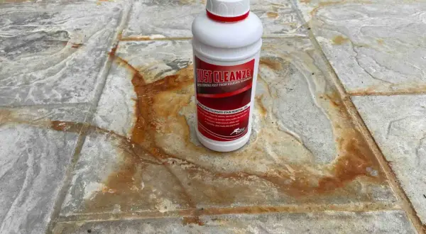 Schody wejściowe z granitu płomieniowanego z plamami rdzy. Butelka środka Rust Cleanze, który pomoże usunąć rdzę.