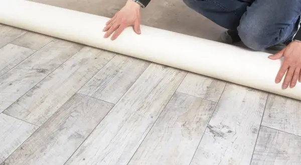 Eine Rolle Unterlage liegt auf einem Holzboden. Sie ist ideal, wenn Sie sich fragen, was kommt unter PVC Boden.