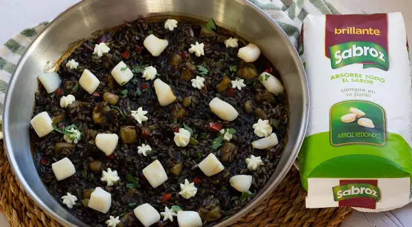 Arroz negro con sepia, adornado con trozos de sepia y puntos de alioli, listo para ser cocinado con arroz redondo Sabroz.