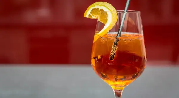 Orzeźwiający Aperol Spritz z plasterkiem pomarańczy i słomką. Idealny przepis na letnie popołudnie.